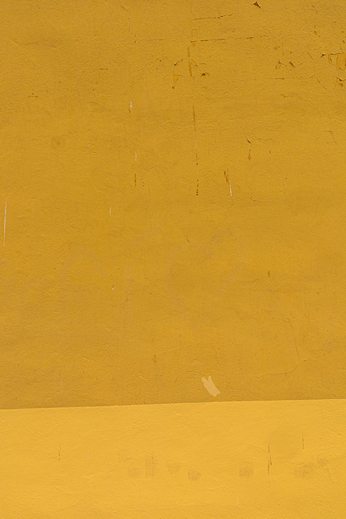 a man riding a skateboard down a street next to a yellow wall