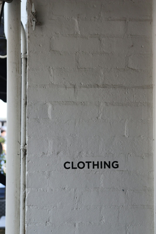 The word clothing is on a brick wall.