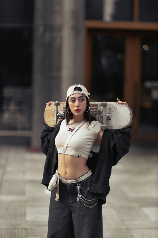 Young woman holding skateboard over shoulders outdoors