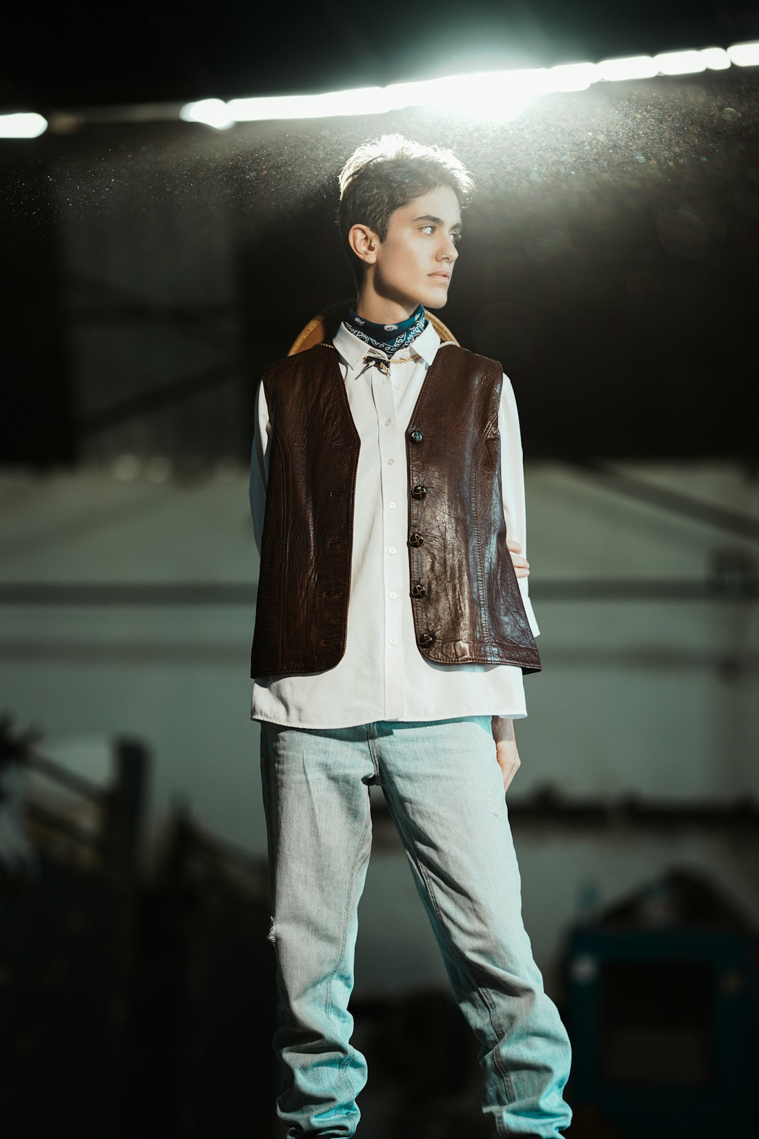 Young man in vest and jeans looking away