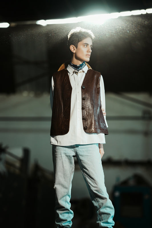 Young man in vest and jeans looking away