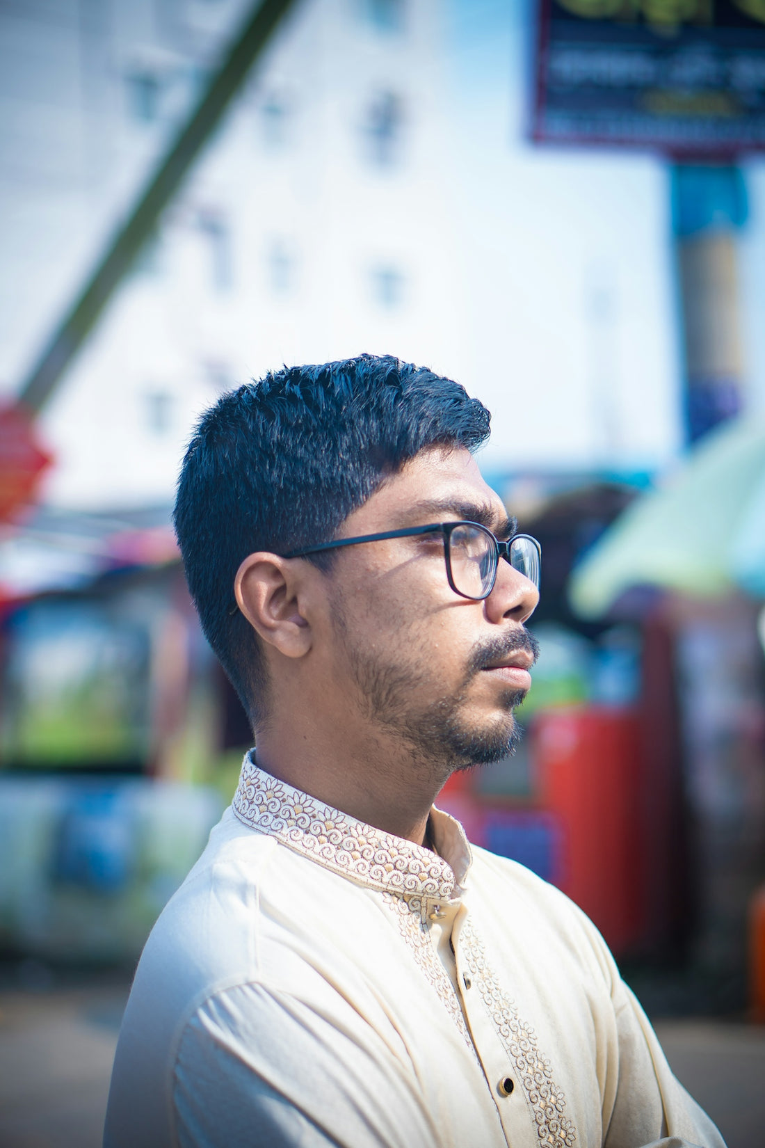 Man wearing glasses and traditional clothing looking away.
