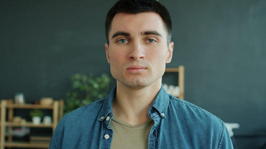 A man in a denim shirt looks forward.