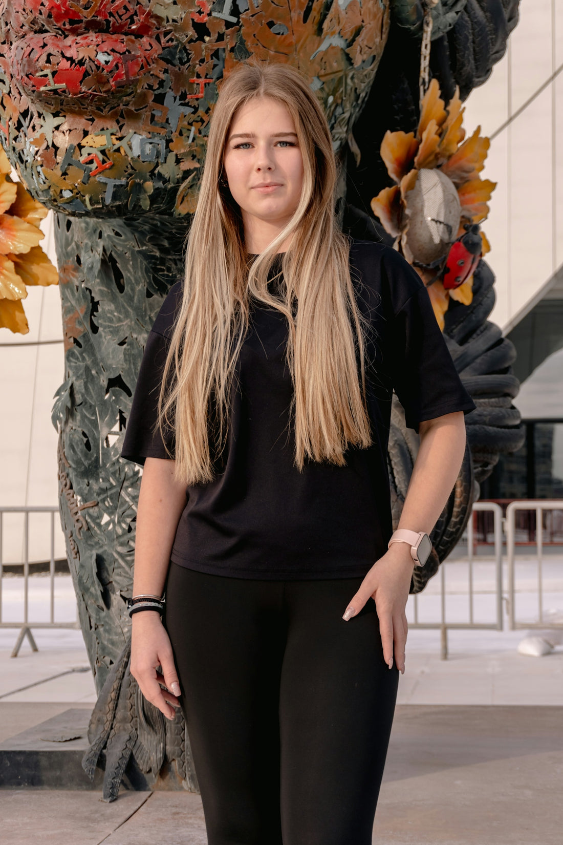 Young woman standing in front of an abstract sculpture.