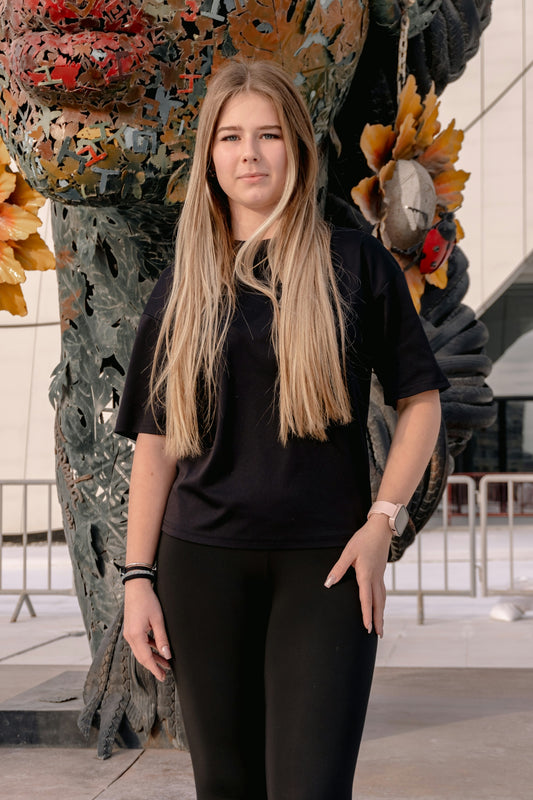Young woman standing in front of an abstract sculpture.