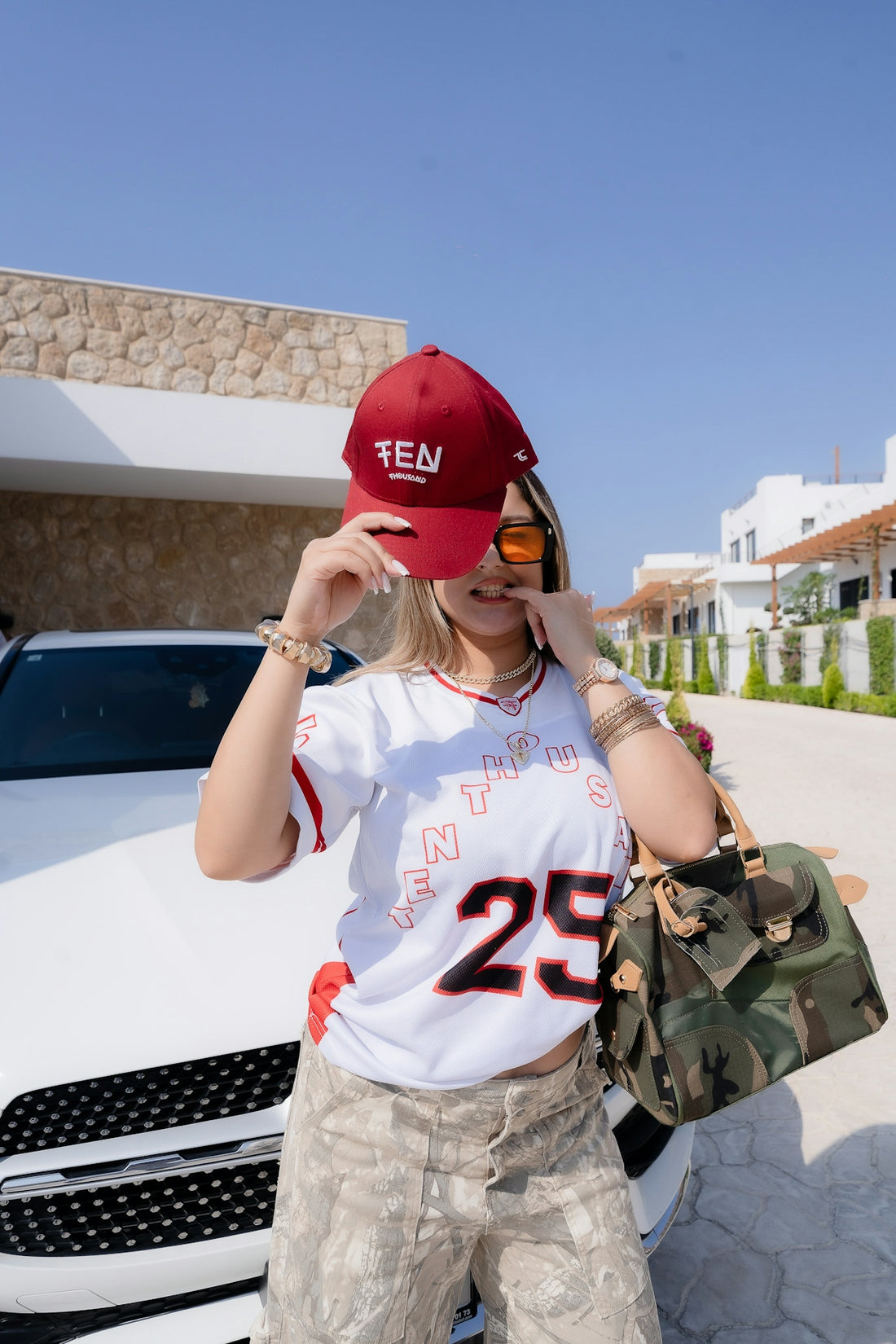 Woman in baseball cap and jersey with car
