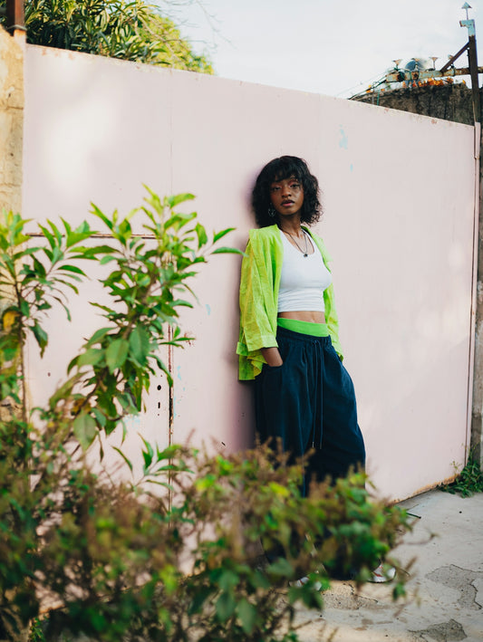 Young woman leans against a pink wall.