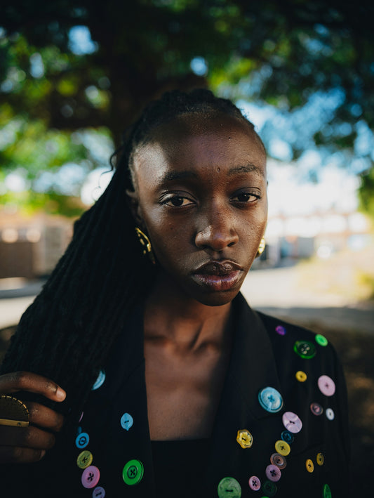 Young black woman with braided hair and colorful jacket.