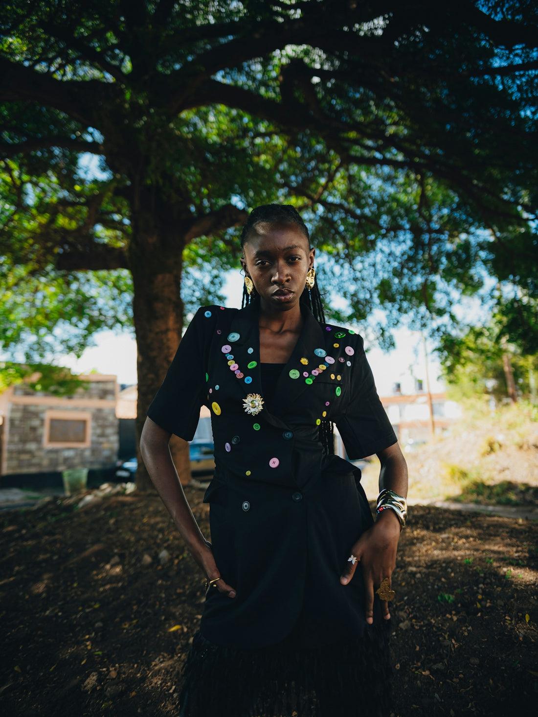 A black woman in a decorated black jacket stands outdoors.
