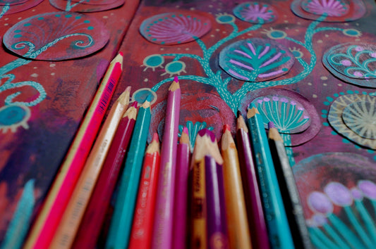 Colored pencils arranged on a textured, artistic background.