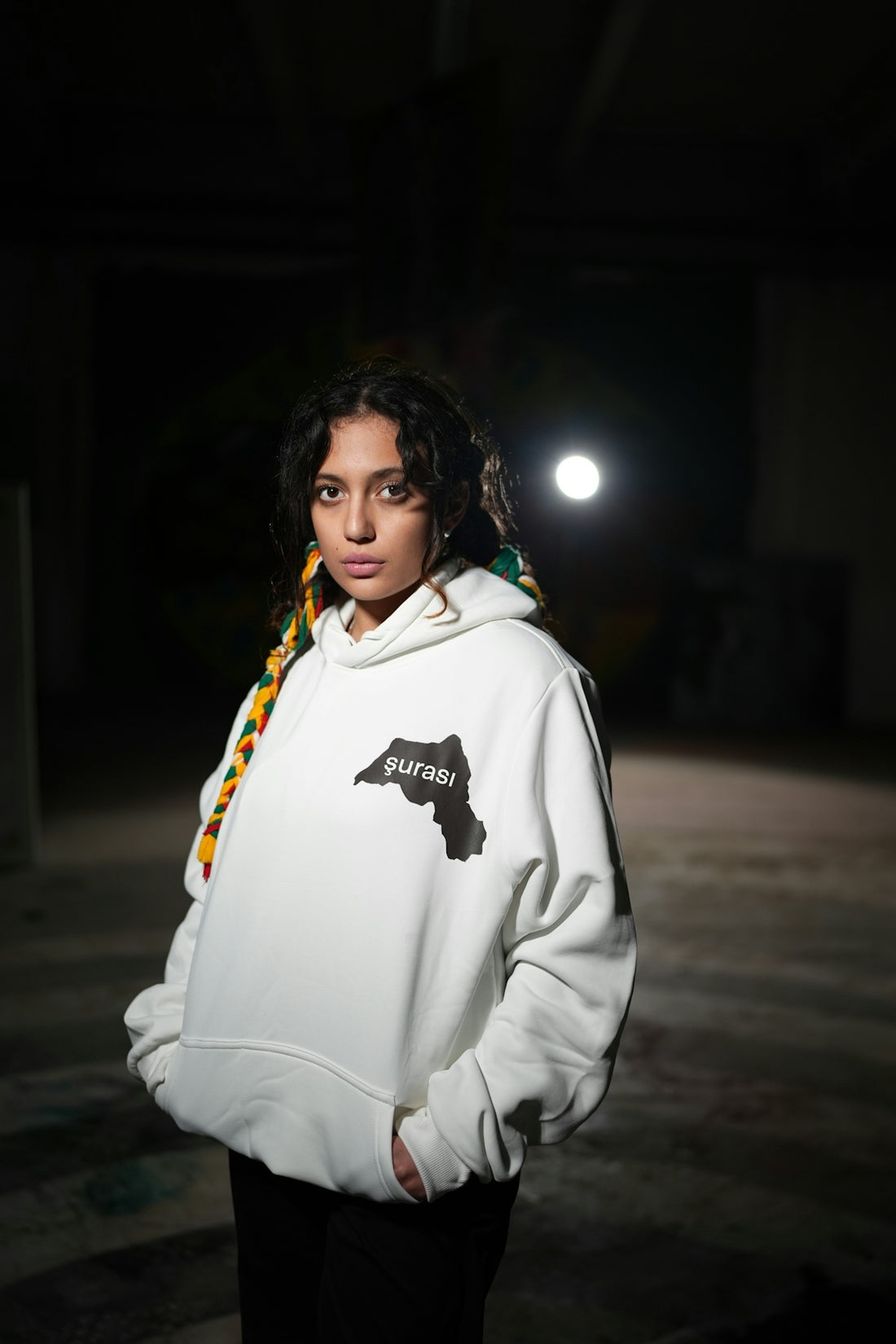 Young woman wearing a white hoodie in dark setting