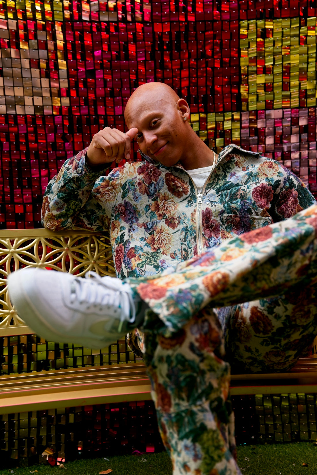 A man in a floral suit sits on a bench.