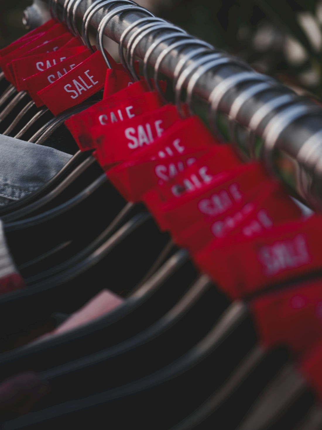 Red sale tags hanging on a clothing rack